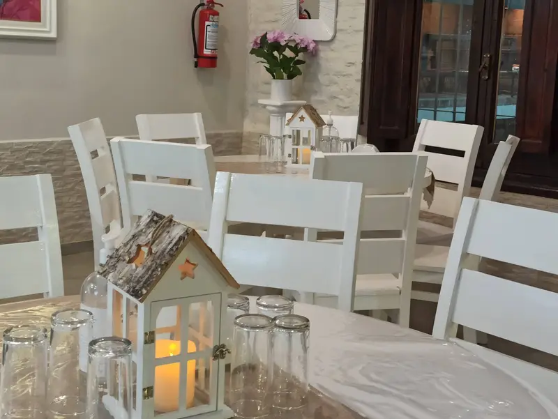 Mesas con mantel blanco, vasos y un farol decorativo en el salón