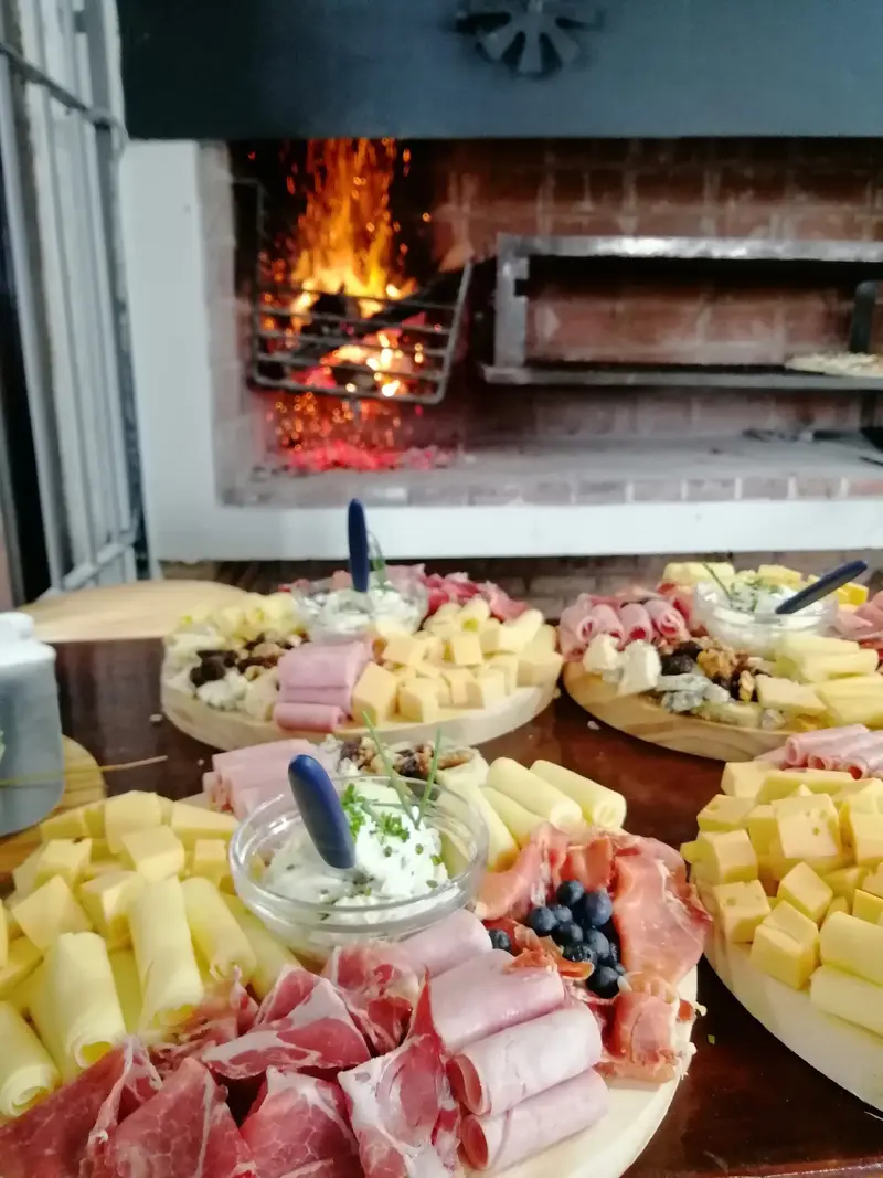 Parrillero encendido y tablas de fiambres y quesos servidas