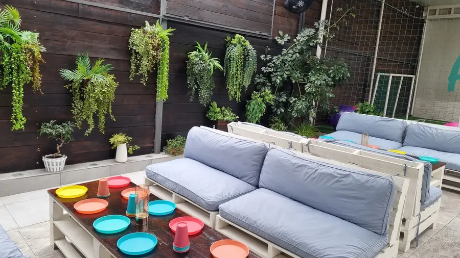 Patio con jardín vertical, sillones de pallets y platos de colores sobre la mesa
